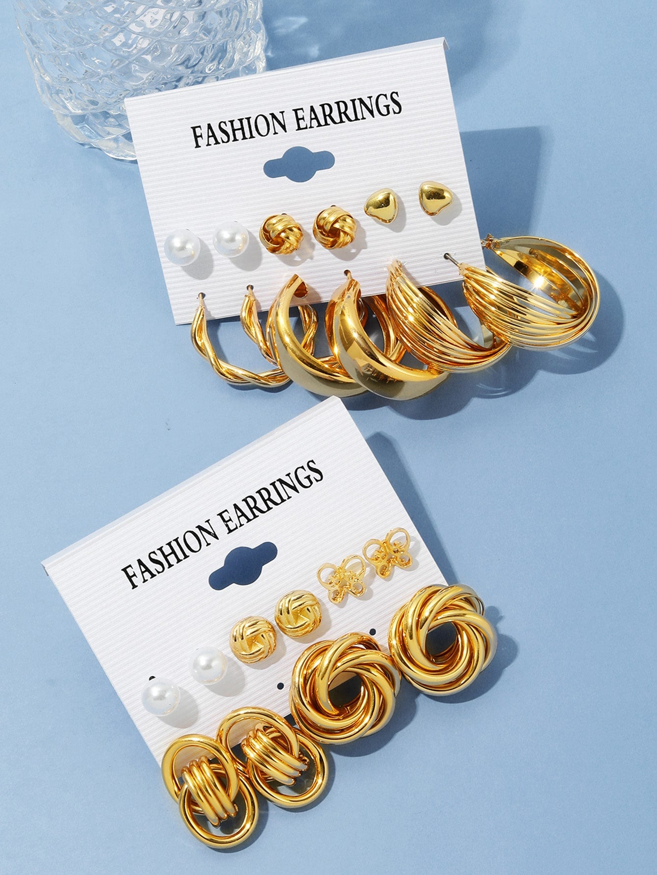 Set of gold and pearl fashion earrings featuring various styles including hoops, knots, hearts, and twists. Displayed on a card labeled 'FASHION EARRINGS' for easy selection and gifting.