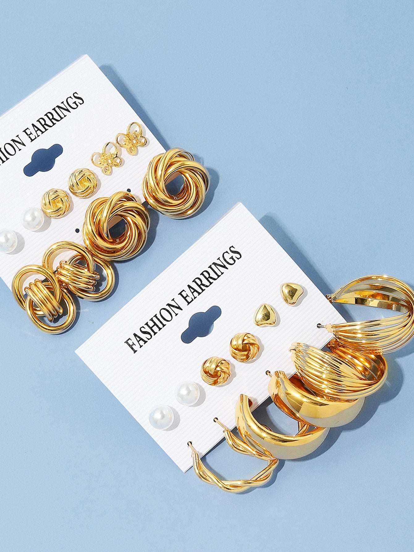Set of gold and pearl fashion earrings featuring various styles including hoops, knots, hearts, and twists. Displayed on a card labeled 'FASHION EARRINGS' for easy selection and gifting.