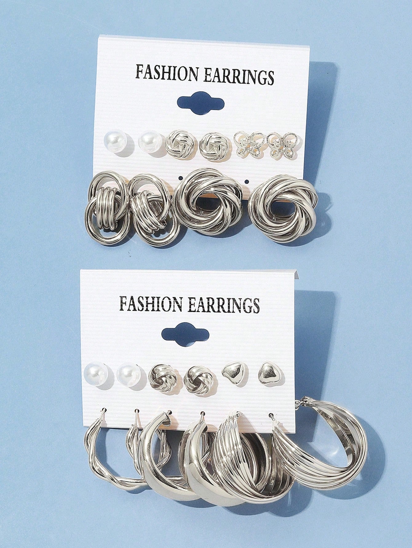 Set of silver and pearl fashion earrings featuring various styles including hoops, knots, hearts, and twists. Displayed on a card for easy selection and gifting.