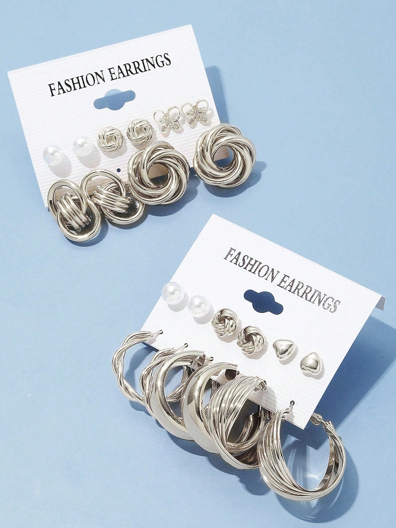 Set of silver and pearl fashion earrings featuring various styles including hoops, knots, hearts, and twists. Displayed on a card for easy selection and gifting.