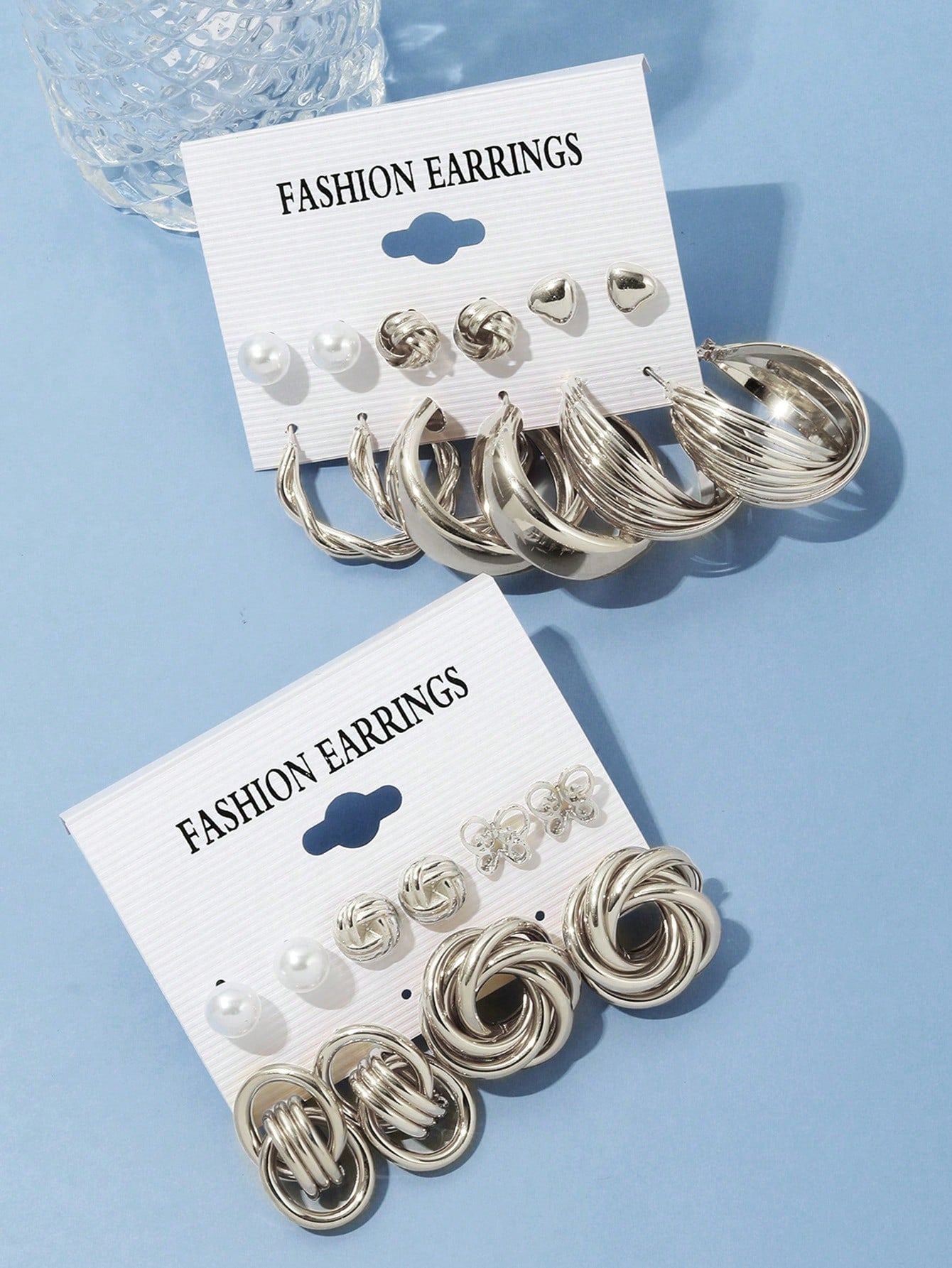 Set of silver and pearl fashion earrings featuring various styles including hoops, knots, hearts, and twists. Displayed on a card for easy selection and gifting.