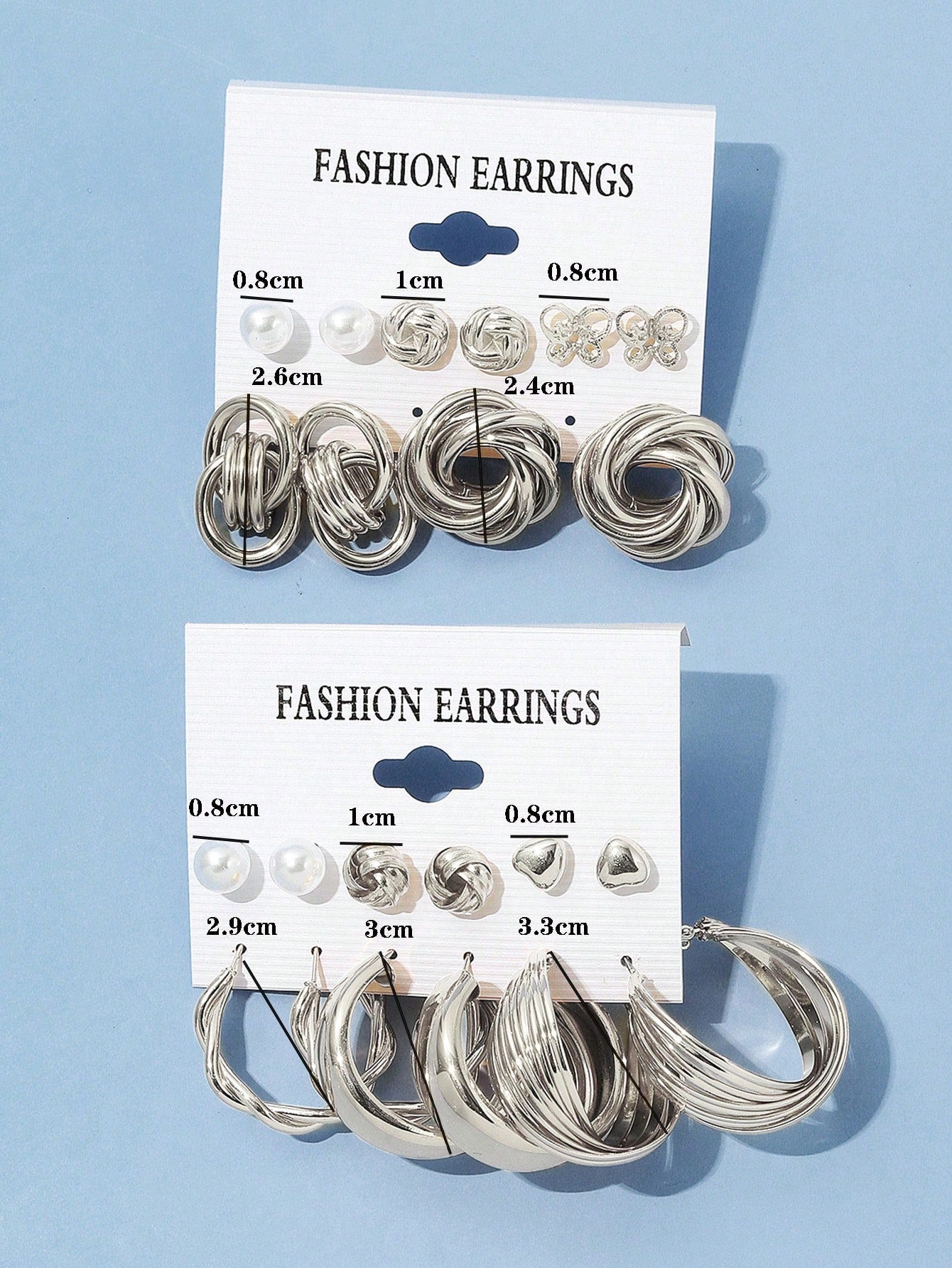 Set of silver and pearl fashion earrings featuring various styles including hoops, knots, hearts, and twists. Displayed on a card for easy selection and gifting.