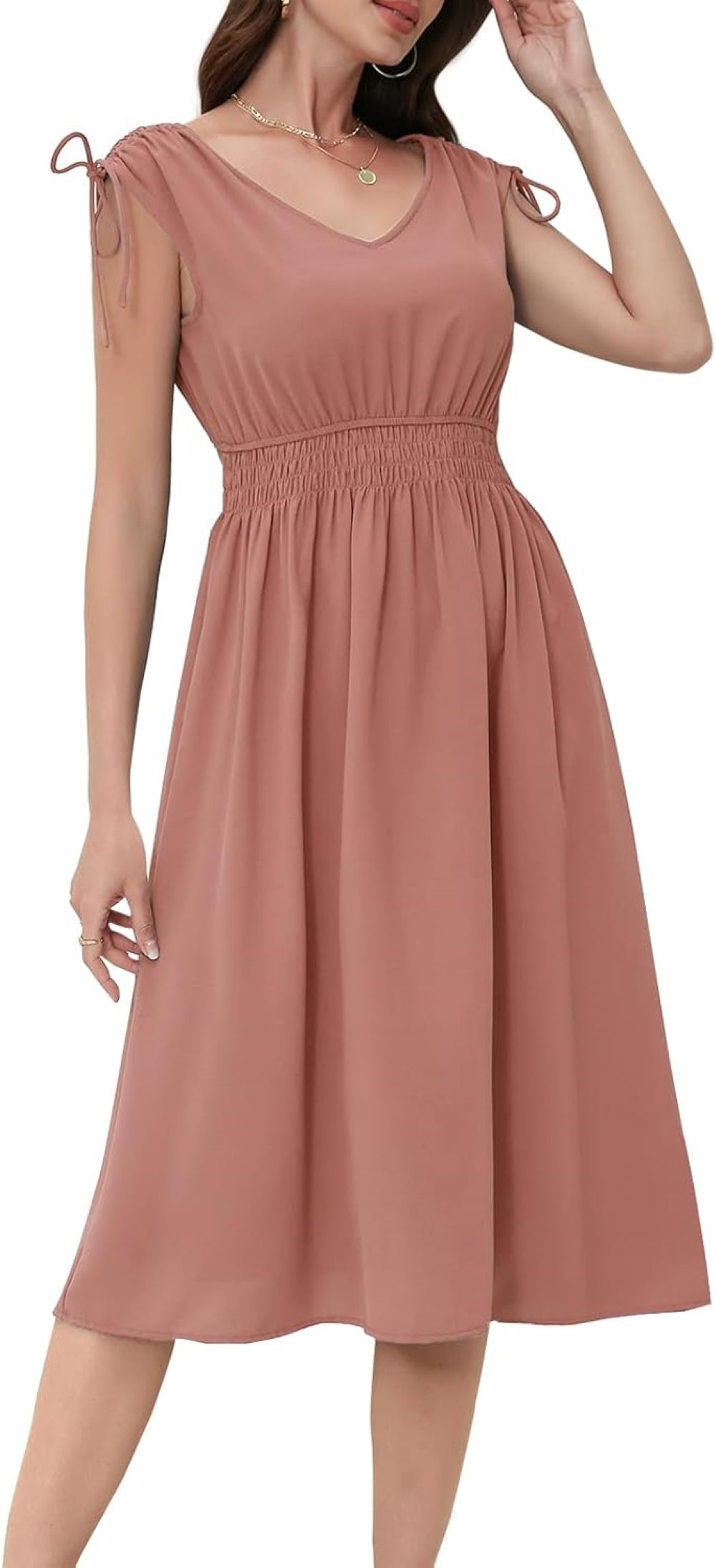 Blush dress with a V-neckline, short sleeves with drawstring ties, elasticated waistband, and a flowy skirt. Paired with gold hoop earrings and layered necklaces. Shown against a plain background.