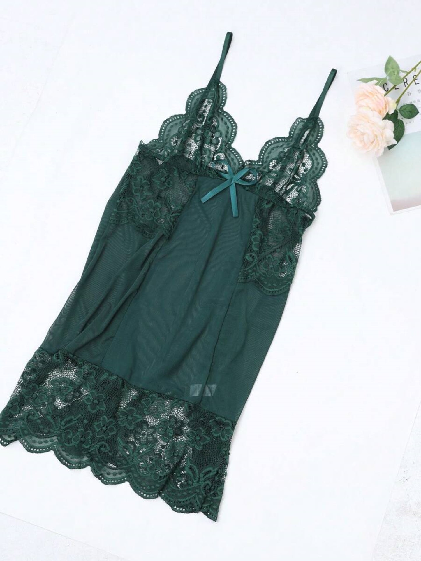 Laid flat green lace and mesh bodysuit with decorative bow.