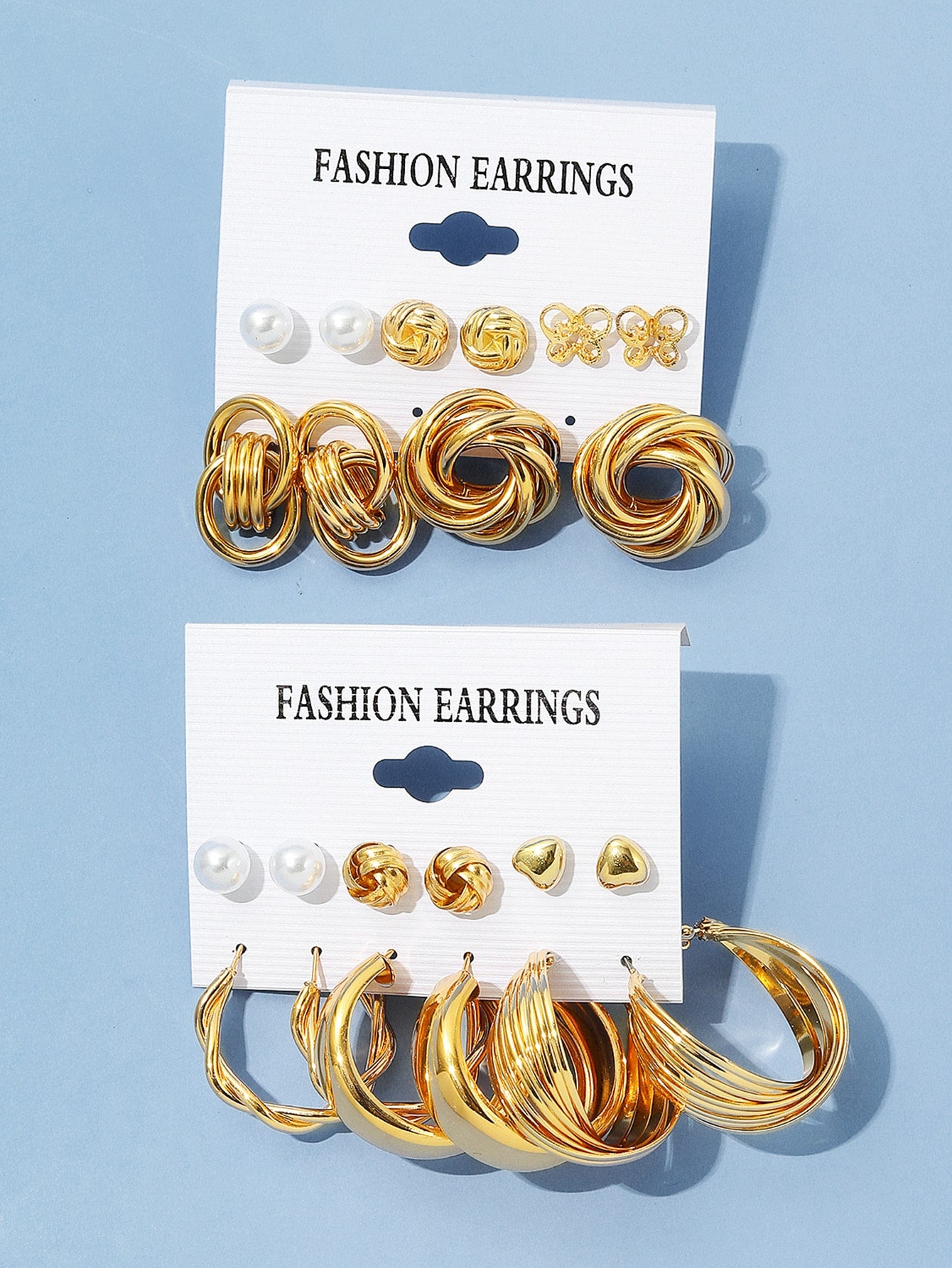 Set of gold and pearl fashion earrings featuring various styles including hoops, knots, hearts, and twists. Displayed on a card labeled 'FASHION EARRINGS' for easy selection and gifting.