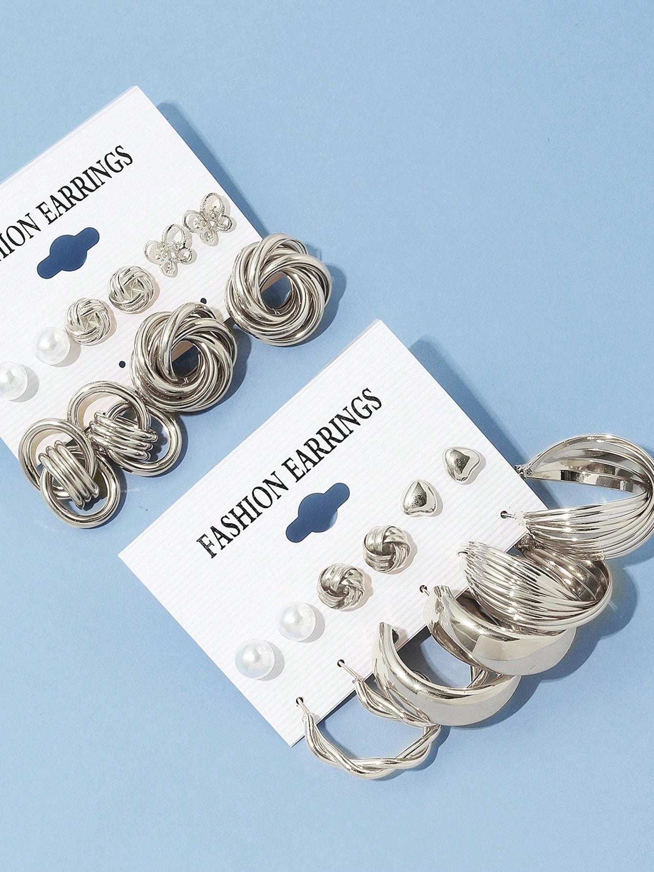 Set of silver and pearl fashion earrings featuring various styles including hoops, knots, hearts, and twists. Displayed on a card for easy selection and gifting.