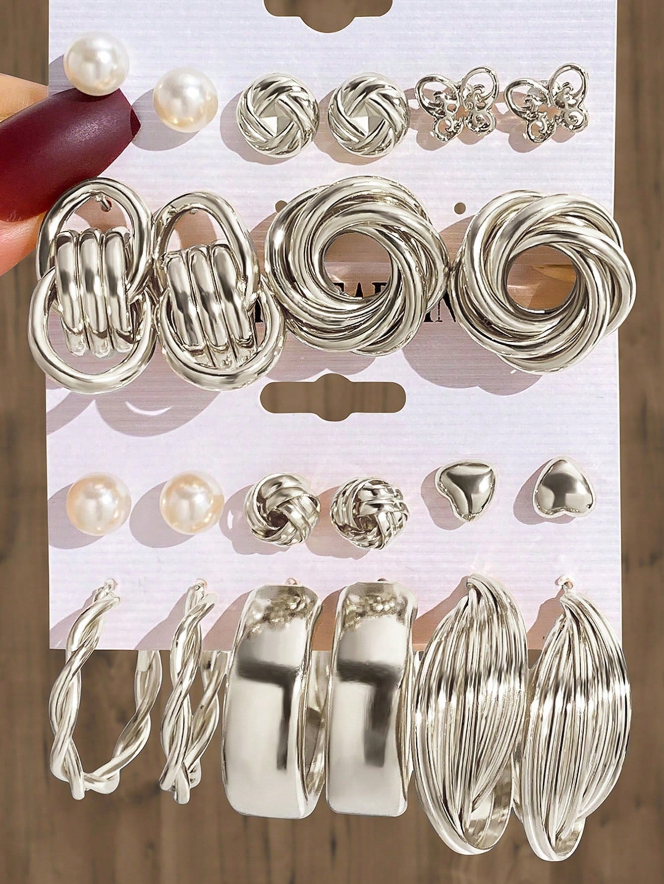 Set of silver and pearl fashion earrings featuring various styles including hoops, knots, hearts, and twists. Displayed on a card for easy selection and gifting.