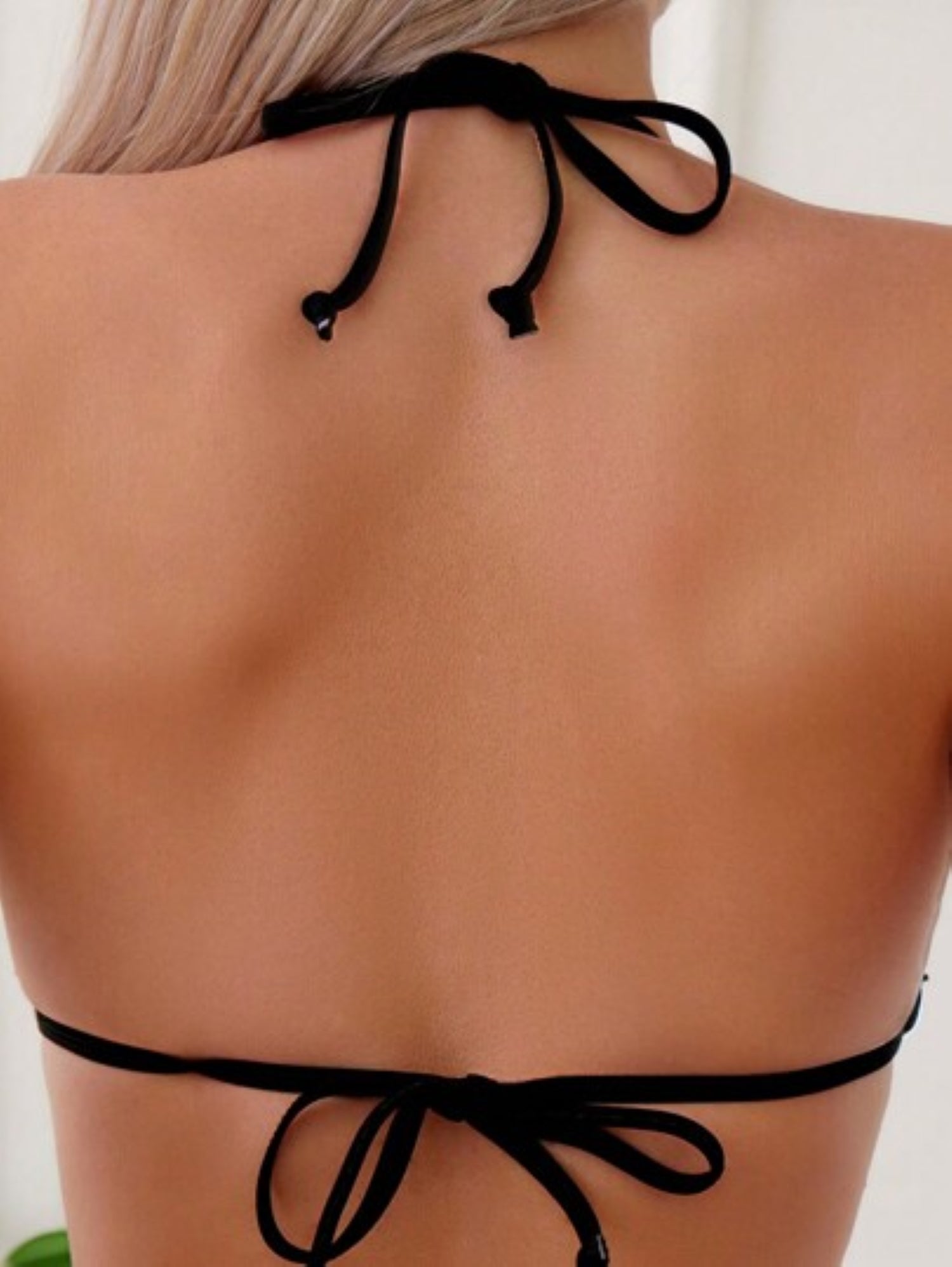 Black bikini top with thin straps on a Model against a white background