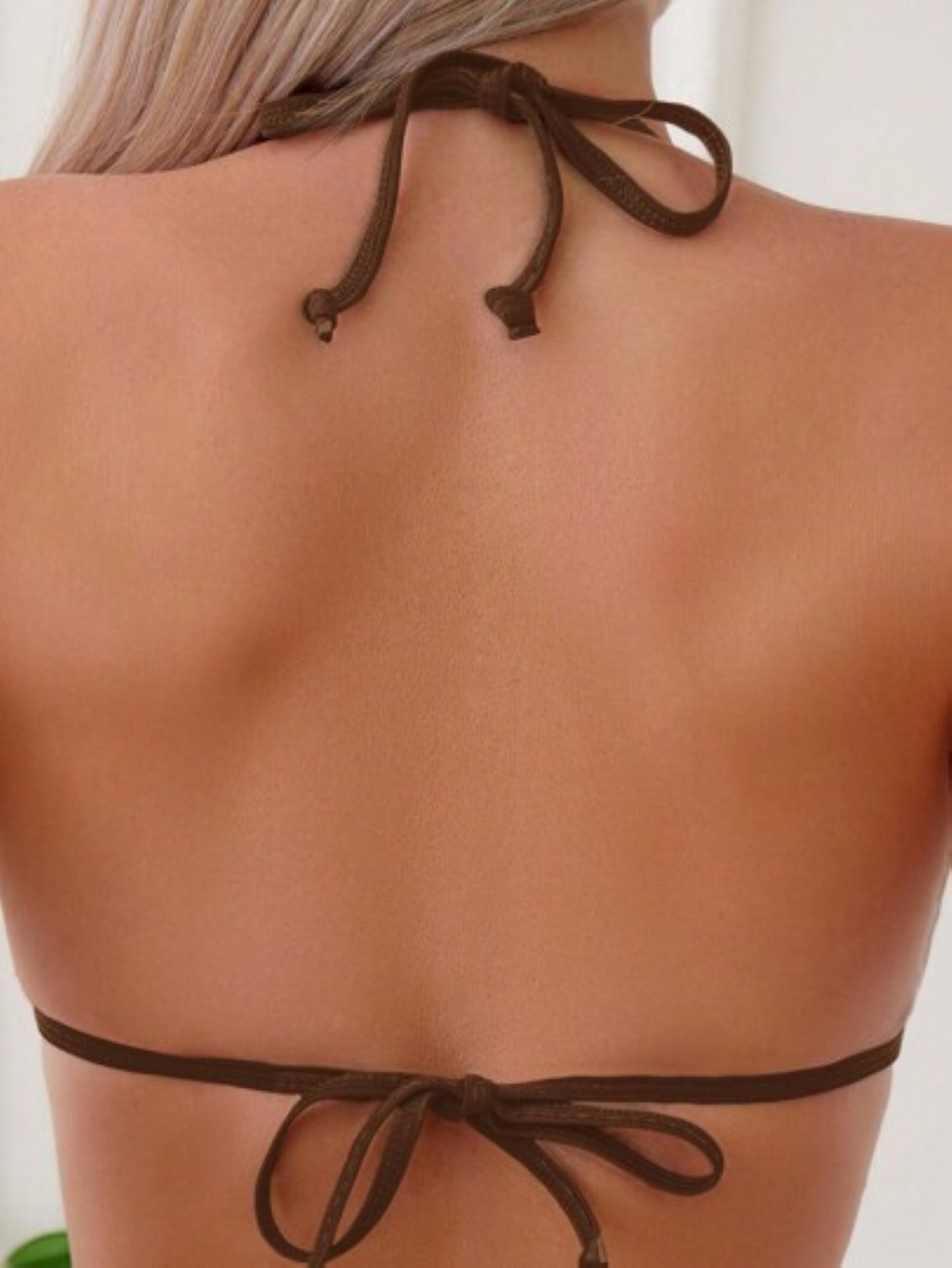 Brown bikini top with thin straps on a Model against a neutral background