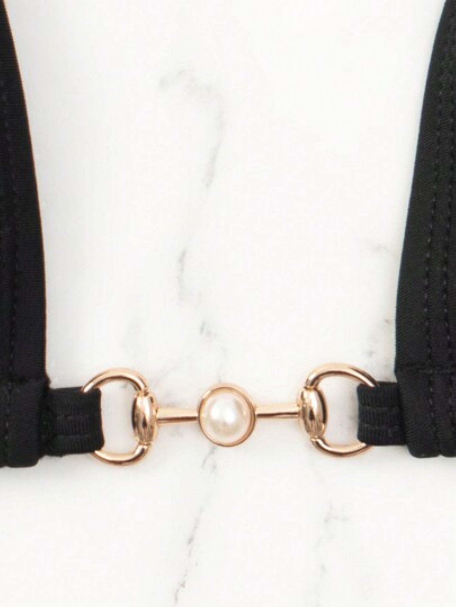 Black choker with gold and pearl detailing on a white background
