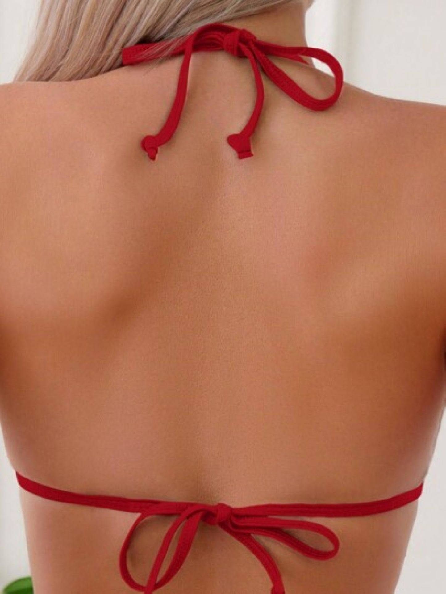 Red bikini top with thin straps on a person against a neutral background