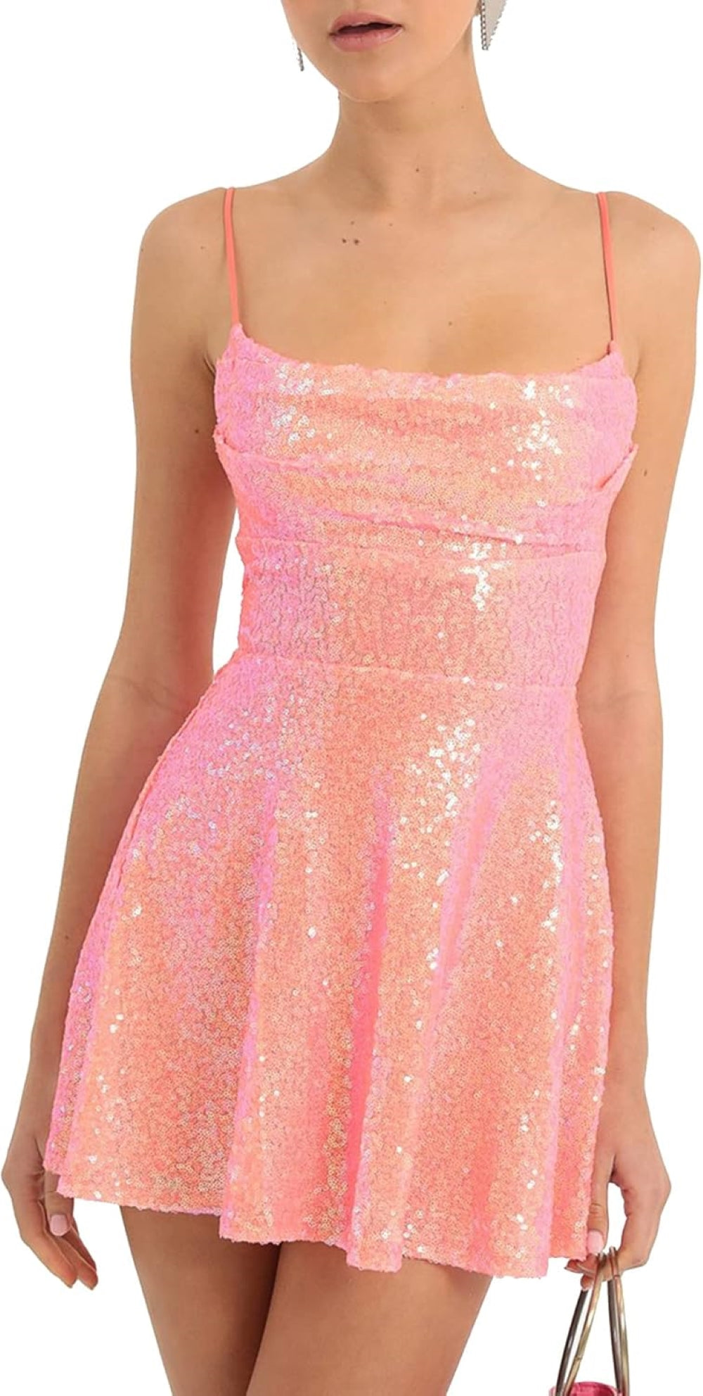 A model wearing a pink sequined mini dress with thin shoulder straps and a flared skirt, holding a pink tasseled handbag