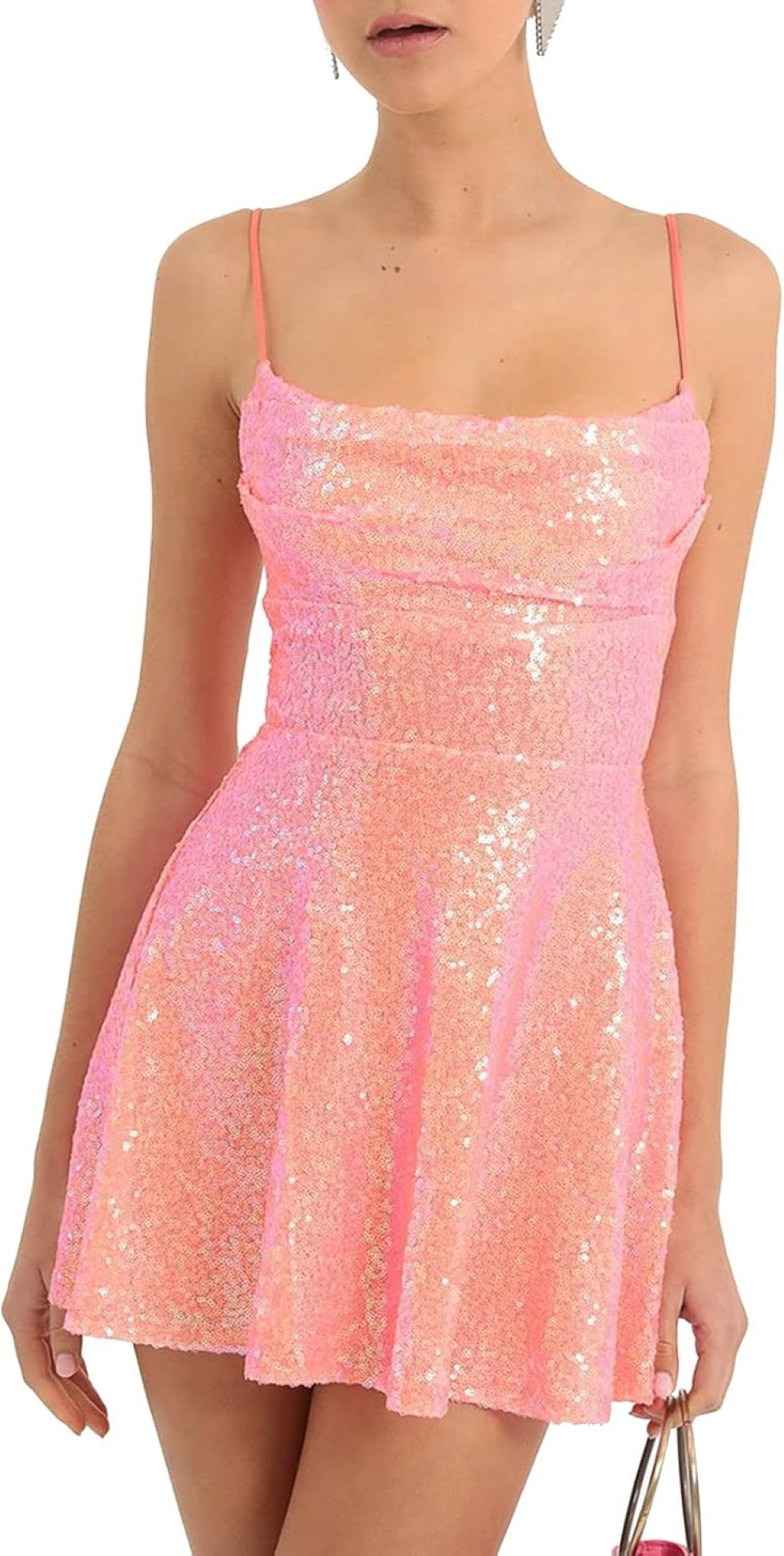 A model wearing a pink sequined mini dress with thin shoulder straps and a flared skirt, holding a pink tasseled handbag