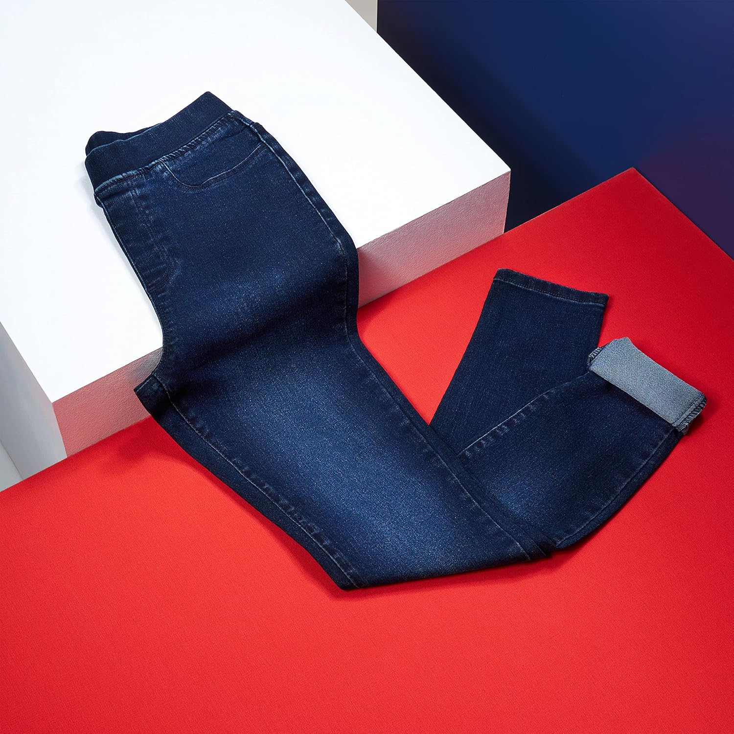 Indigo-Blue denim jeans styled on a mannequin, displayed against a red and white background with a box.