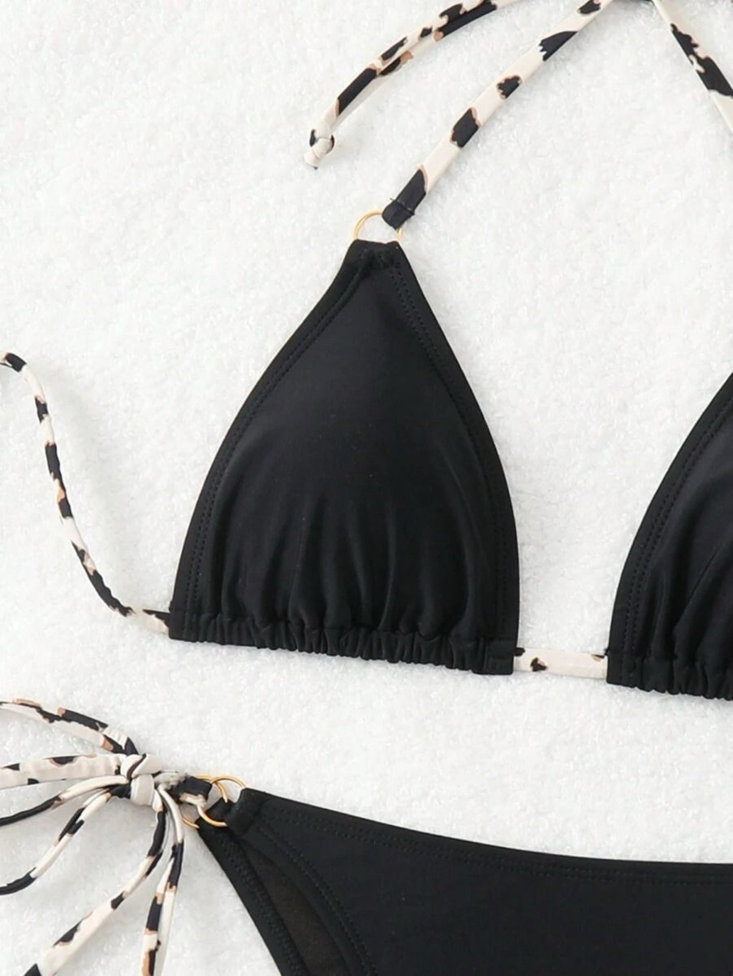 Black bikini top with leopard print straps on a white background